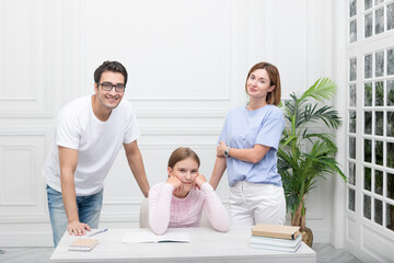 Fototapeta premium Portrait of happy family with child daughter studying at home. Home education and parents support concept 