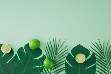 Creative trendy summer layout made with lime and tropical green palm leaves on pastel green background with copy space.  Minimal summer fruit concept. Nature monochromatic flat lay. Top of view.