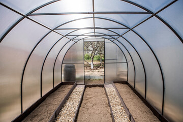 A new greenhouse made of polyethylene and polycarbonate with new beds made of Wood-polymer composite. Preparing for the spring garden season. Installation of a greenhouse in a suburban area.