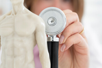 Young beautiful female doctor checking up with stethoscope a human model mock up in office of the...