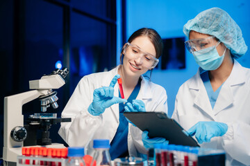 Modern Medical Research Laboratory Portrait of Two Scientists Working, Using Digital Tablet,...