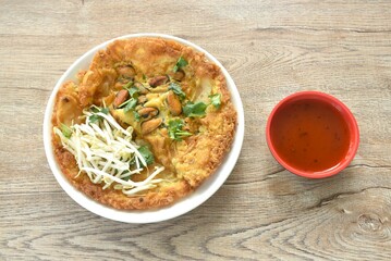 crispy fried egg and flour stuffed mussel with bean sprout on plate dipping chili sauce