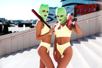 Two beautiful sexy women in green underwear. Models wearing bandit balaclava mask. Hot seductive...