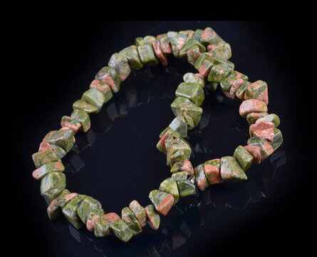 Unakit stone  braceleton a black background . Bracelet made of stones on hand from natural Carnelian. Handmade jewelry bracelets ..