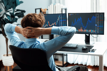 Young investor stock trader leaning body back looking at investing dynamic screen of current market...