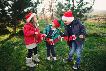 3 lovely brothers and sister holding Merry Christmas sign
