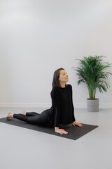 person in black clothes practices yoga in the Urdhva Mukha Svanasana upward-facing dog pose. Taking care of the body mental health. A woman strives Harmony, balance and healthy lifestyle. Yoga Center
