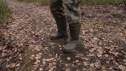 Feet in rubber boots on a forest, rural road.