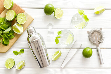Bartender desktop with utensils and mojito cocktail. Lime with mint and ice cubes, top view
