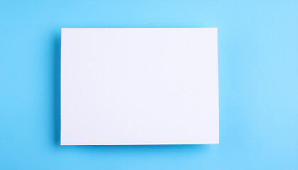 Mock-up of white blank card sheet of paper on bright blue surface. Postcard template. Top view