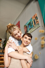 Tender embrace between two women, one holding the other in her arms at an art studio.