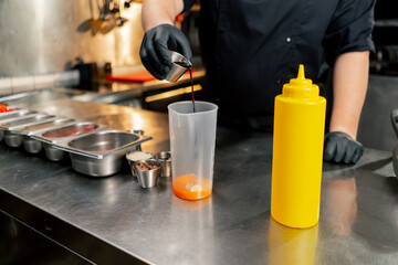 in a professional kitchen the chef prepares a sauce for salad adding ingredients step by step