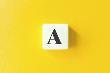 Capital Letter A. Text on Block Letter Tiles against Yellow Background.