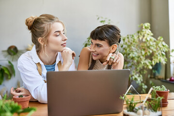 Two women in an art studio, engrossed in the laptop screen.