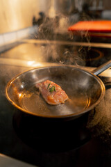 close up in a professional kitchen a piece of chicken fillet is fried in small frying pan