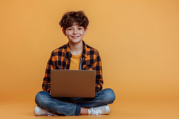 Young smiling student dressed in casual clothes working with a laptop sitting in lotus pose isolated on a studio background.
