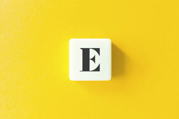 Capital Letter E. Text on Block Letter Tiles against Yellow Background.