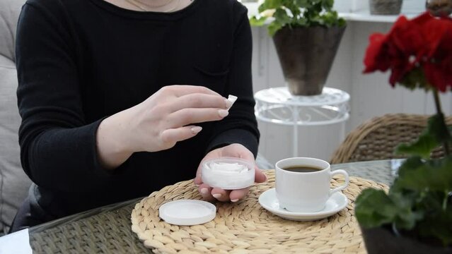 A girl opens a box of snus and takes one bag.	