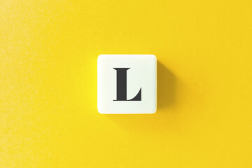 Capital Letter L. Text on Block Letter Tiles against Yellow Background.