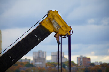  The telescopic boom of a crane against the sky and city on the horizon, construction work with a...