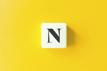 Capital Letter N. Text on Block Letter Tiles against Yellow Background.