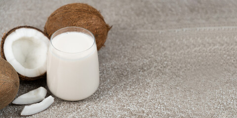 Coconut milk in a glass on a grey background, banner with place for text