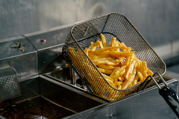 close-up in a professional kitchen the chef takes out french fries from the fryer