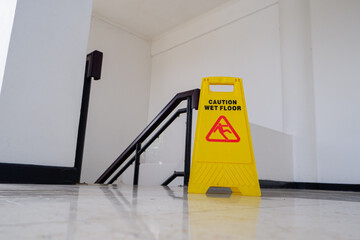 wet floor yellow warning board with out of focus stairs background