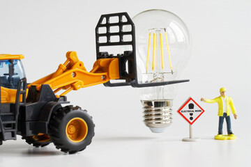 Toy tractor and worker preparing to install and mounting LED lamp. Electrical transportation and...