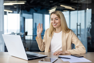 Professional woman in office greeting via laptop video call