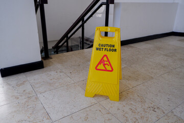 wet floor yellow warning board with out of focus stairs background