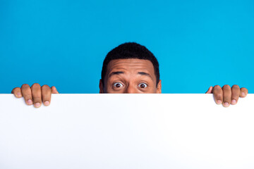 Photo of nice young man hide face behind empty space blank isolated on blue color background