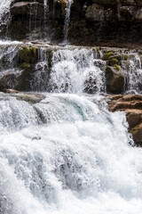 a lively waterfall cascading over rocks, surrounded by moss, embodying the energy and beauty of nature