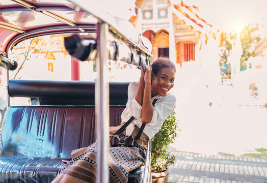 cheerful black tourist girl head out from tuk tuk ride. happy solo traveler girl holding steel bar enjoying air flow on tuk. african american young tourist using bar headout for air on ride tuk tuk