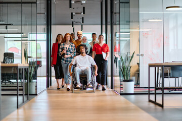 A diverse group of young business people walking a corridor in the glass-enclosed office of a...