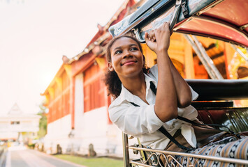 happy black traveler girl head out from tuk tuk ride. african american young tourist using bar headout for air on ride tuk tuk. cheerful solo tourist girl holding steel bar enjoying air flow on tuk