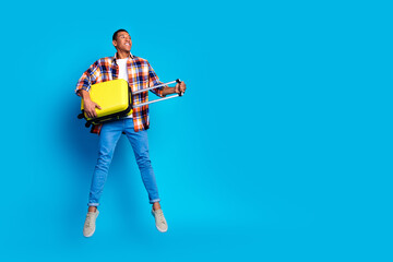 Full body portrait of nice young man suitcase jump look empty space wear shirt isolated on blue color background