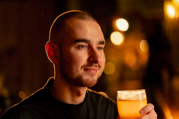 close-up on a wooden bar table guy holds a glass of light beer warm lighting light