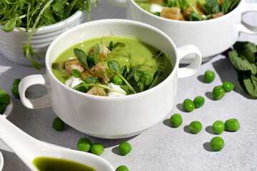 Refreshing Summer Pea Soup with Crispy Croutons, Sour Cream, Fragrant Mint, Pea Shoots, and Vibrant Parsley Oil. Plant-Based Food Inspiration. Handcrafted Image, Not AI