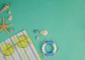 on a delicate green-blue background, shells of different shapes and sizes, a beach towel, yellow...