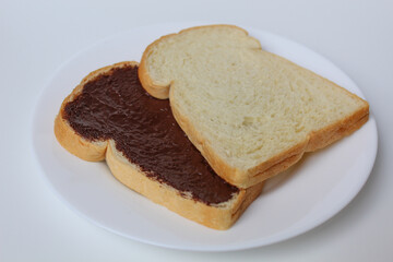 Two slices of white bread with chocolate spread or chocolate jam. Chocolate sandwich. On white plate, isolated on white background