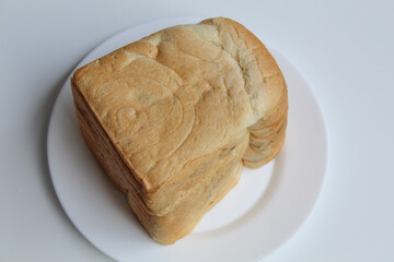 One loaf of slightly moldy white bread, on white plate, isolated on white background