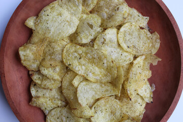Thin slices of potato chips with seaweed seasoning, on wooden plate, isolated on white background,...