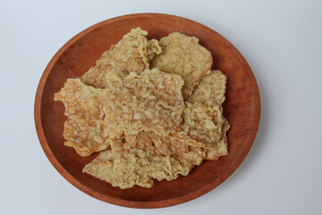 Keripik tempe or tempeh crackers, square shape. Thin slices tempeh, fried with flour dough. On wooden plate, isolated in white background