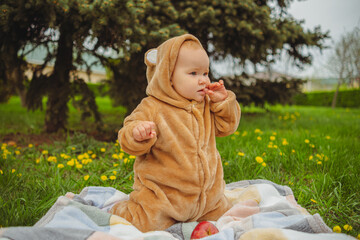 Baby in Bear Costume Sitting on Blanket. A baby wearing a bear costume sitting on a blanket in a...