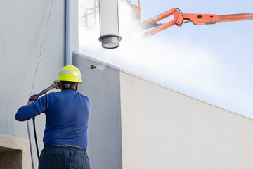 Worker cleaning a building facade with high pressure water jet. Copy space