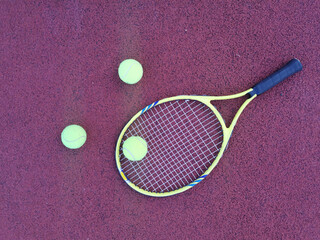 Tennis. Tennis ball and racket on a red background of tennis court with copy space. Sport and...