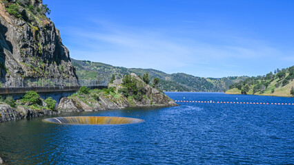 glory hole spillway in a lake with blue sky and mountain