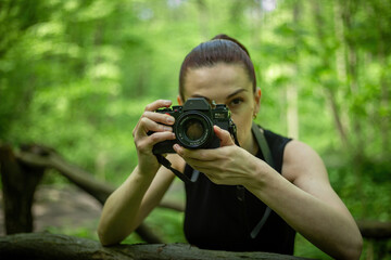 Girl with a camera exploring the lush green forest, capturing its beauty through the lens of her camera.