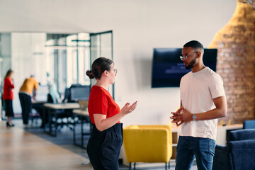 Young business colleagues, including an African American businessman, engage in a conversation about business issues in the hallway of a modern startup coworking center, exemplifying dynamic problem
